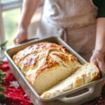Freshly baked no knead bread loaf in a pan with golden crust